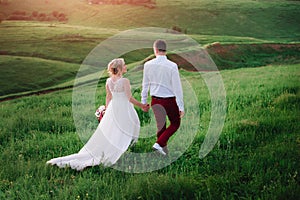 Lovely couple, bride and groom posing in field during sunset, lifestyle