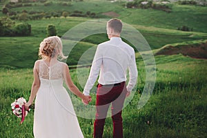 Lovely couple, bride and groom posing in field during sunset, lifestyle