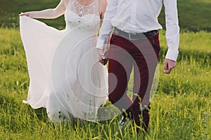 Lovely couple, bride and groom posing in field during sunset, lifestyle