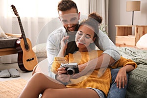 Lovely couple with camera on floor in bedroom