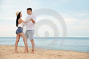 Lovely couple dancing on beach near sea. Space for text