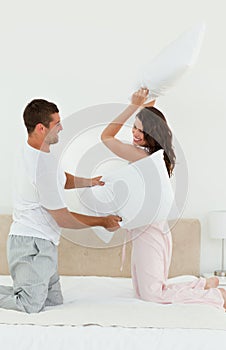 Lovely couple doing a pillow fight on their bed