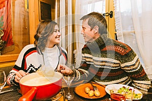 Lovely couple eating traditional swiss cheese fondue