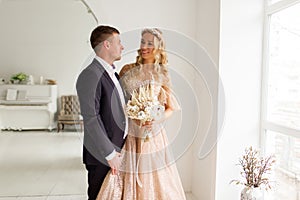 Lovely couple groom and bride in studio with light white interior. Wedding concept.