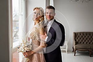 Lovely couple groom and bride in studio with light white interior. Wedding concept.