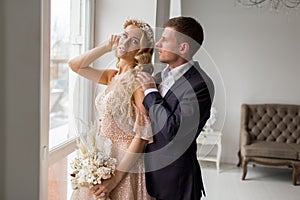 Lovely couple groom and bride in studio with light white interior. Wedding concept.