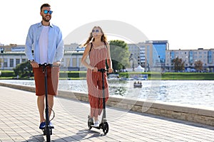 Lovely couple having fun driving electric scooter along the city promenade