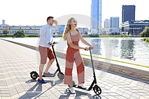 Lovely couple having fun driving electric scooter along the city promenade