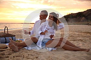 Lovely couple having romantic picnic on beach