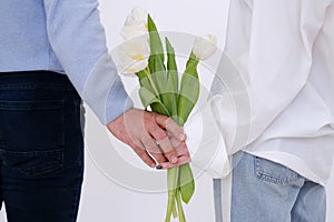 Lovely couple holding hands and a bouquet of white tulips