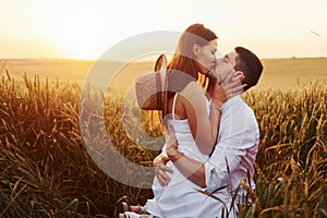 Lovely couple kissing and spending free time on the field at sunny day time of summer