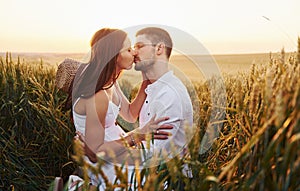 Lovely couple kissing and spending free time on the field at sunny day time of summer