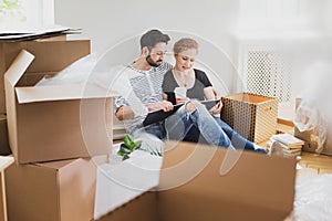 Lovely couple looking at photo album while unpacking stuff after relocation to new home