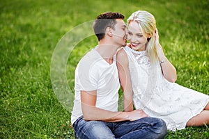 The lovely couple in love sitting on green grass.