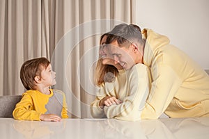 Lovely couple, parents, mom and dad with their child son sitting by the table and having fun
