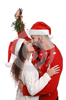 Lovely couple in Santa hats under mistletoe bunch on white background