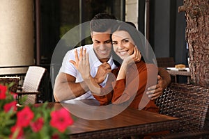 Lovely couple showing beautiful engagement ring in outdoor cafe