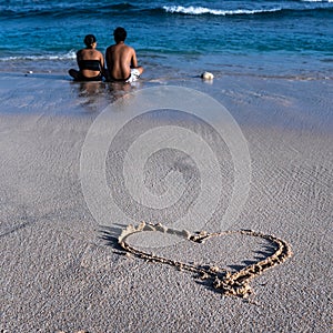 Lovely couple sitting on the beach and enjoing the sea