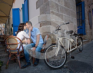 Lovely couple sitting in sidewalk cafe near their tandem bicycle