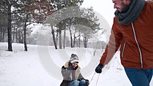 Lovely couple sledding on snowy winter day. Man pull sled with girlfriend on snowfall. Woman have fun and sledge