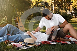 Lovely couple spending time together on plaid in park