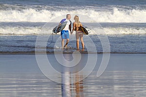 Lovely couple with surfboards on beach.