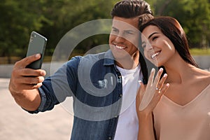 Lovely couple taking selfie after they got engaged outdoors