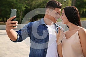 Lovely couple taking selfie after they got engaged outdoors