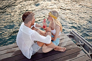 Lovely couple talking on wooden dock and eating watermelon by sea. Summertime holiday fun. Travel, love, fun, togetherness,