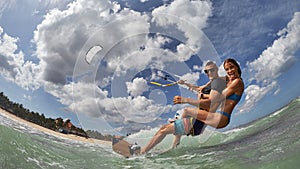 Lovely couple up on one kite board. Woman Riding On Kite surfer`s Back
