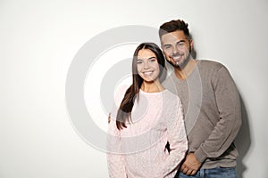 Lovely couple in warm sweaters on light background. Space for text