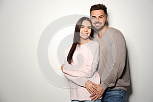 Lovely couple in warm sweaters on light background. Space for text