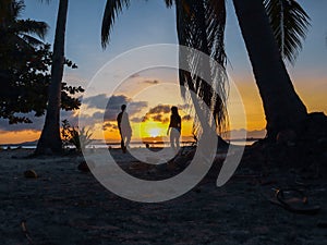 Couple watching sunset with palm trees in Candaraman Island in Balabac Philippines