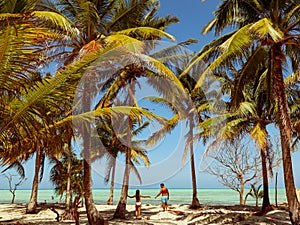 Lovely couple on the white sandy beach, turquoise water and palm trees in Onok island in Balabac, Palawan in Philippines