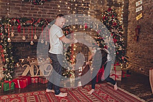 Lovely couple woman and man are fighting with pillows at home near fireplace. Christmas time.