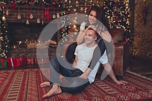 Lovely couple woman and man are sitting at home near fireplace. Christmas time.