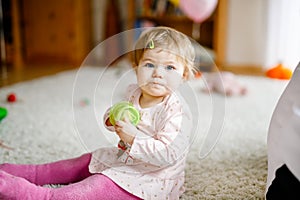 Lovely cute beautiful little baby girl playing with educational toys at home or nursery. Happy healthy child having fun