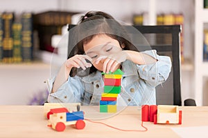 Lovely cute little Asian girl in jeans shirt playing wood block