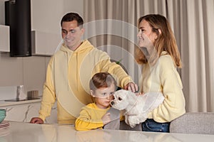 Lovely cute parents in yellow clothes, mom and dad with child son and little white dog