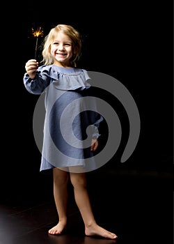 Lovely Excited Girl Wearing Blue Dress Looking at Fire Sparklers
