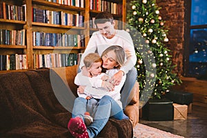 Lovely family with baby son dressed in the same clothes have fun on sofa at home during Christmas. Family Christmas Concept. Happy