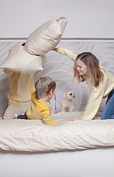 Lovely family, mom and dad with adorable child son playing with pillows