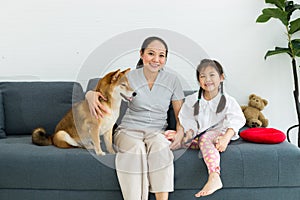 Lovely family, mother and daughter with their favorite dog sit on sofa