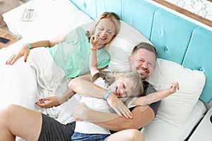 Lovely family rest in bed, father mother and daughter hug in morning