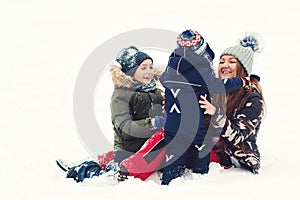 Lovely family in winter. Pretty mother and two sons having fun together while lying on snow. Happy christmas holidays
