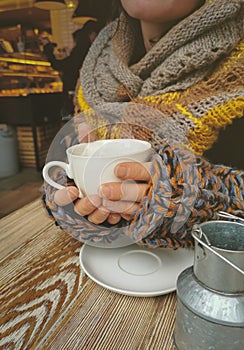 Lovely female hands holding a white Cup of hot coffee. A girl in a Cozy warm knitted sweater holding a Cup of hot coffee