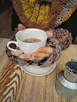 Lovely female hands holding a white Cup of hot coffee. A girl in a Cozy warm knitted sweater holding a Cup of hot coffee