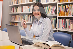 Půvabný žena pracovní na přenosný počítač na knihovna 
