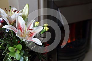 Lovely festive Christmas flower arrangement with lilies and carnations, fireplace in background, copy space for text