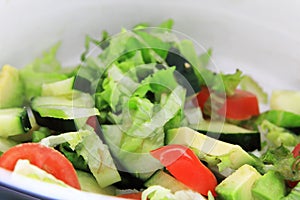 A lovely, fresh bucket of salads gives a meal the essential balance to feed a hungry body. Tomatoes, cucumber, avacado and lettuce photo